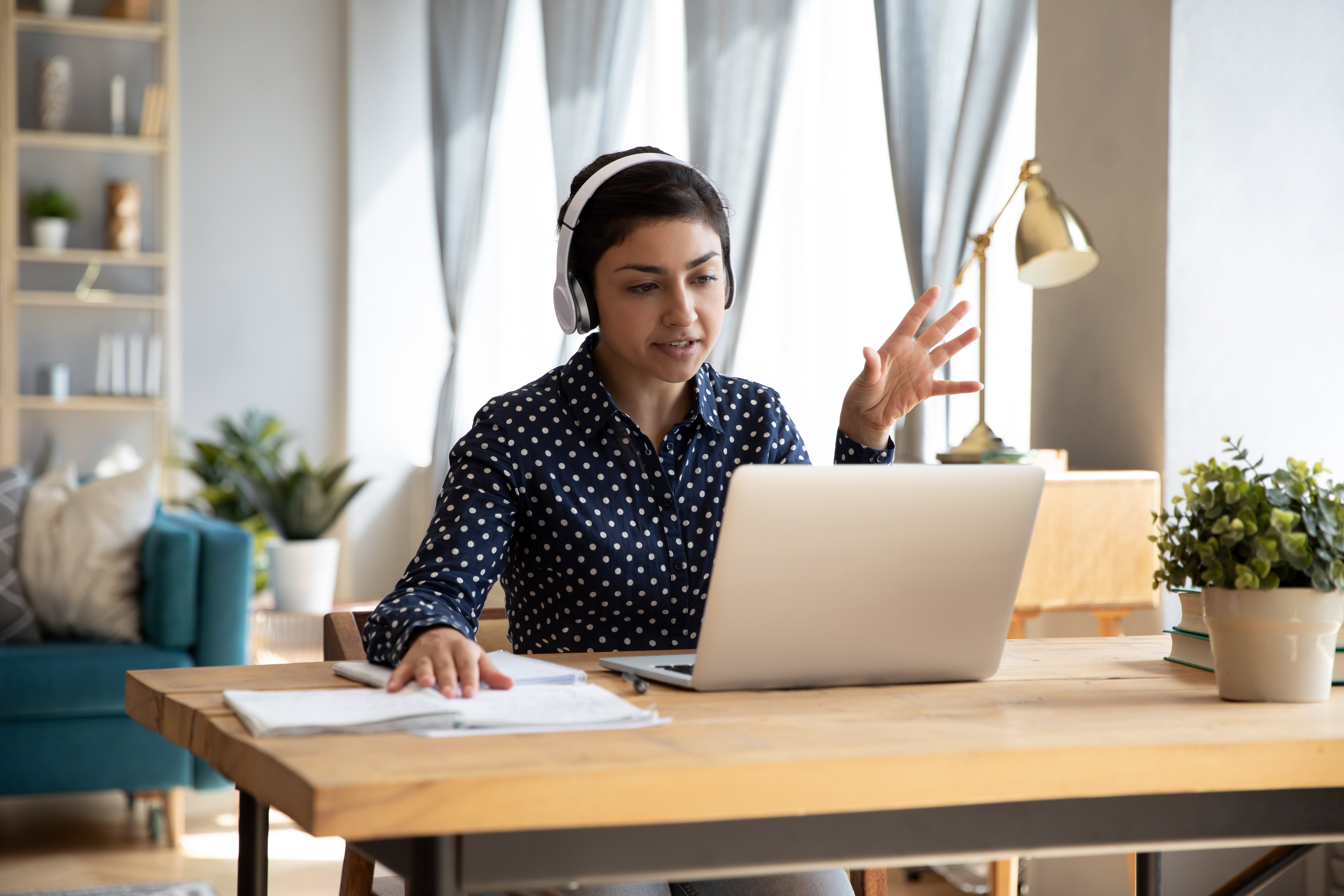 Woman with headset working on laptop from home
