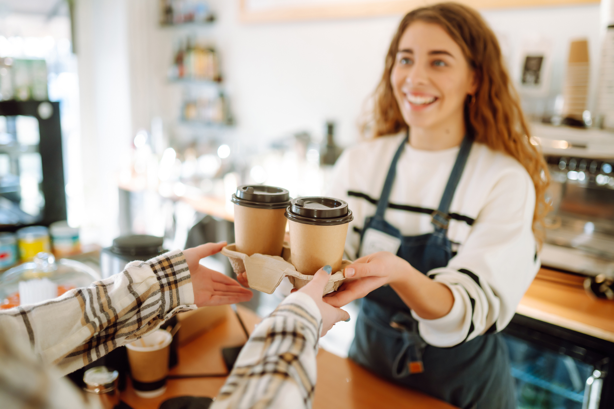 Smiling employee serves coffee to customer